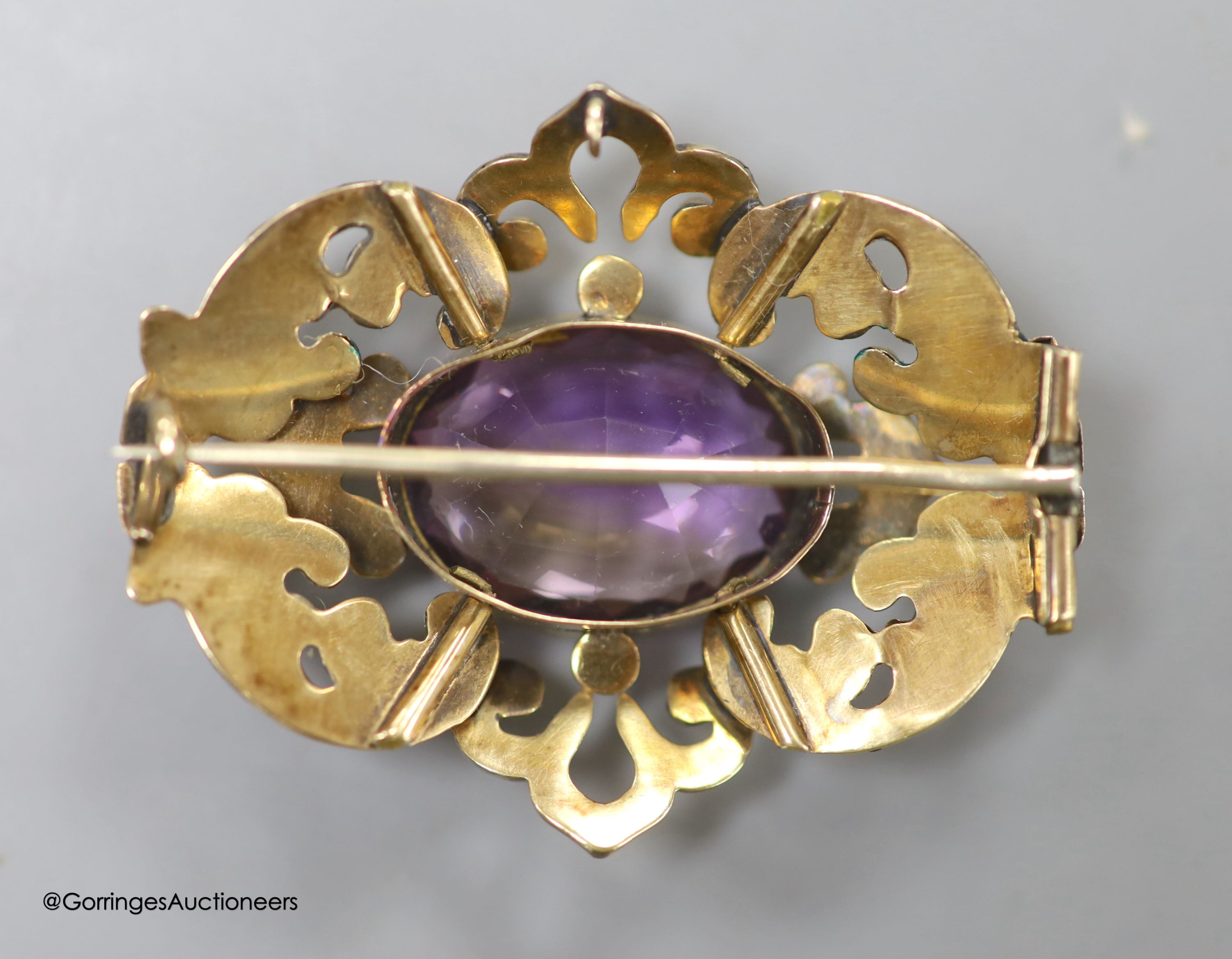 A cased late Victorian yellow metal and amethyst set pierced scroll brooch, 45mm